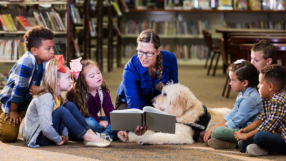 civic-vision Woman reading book to group of children.